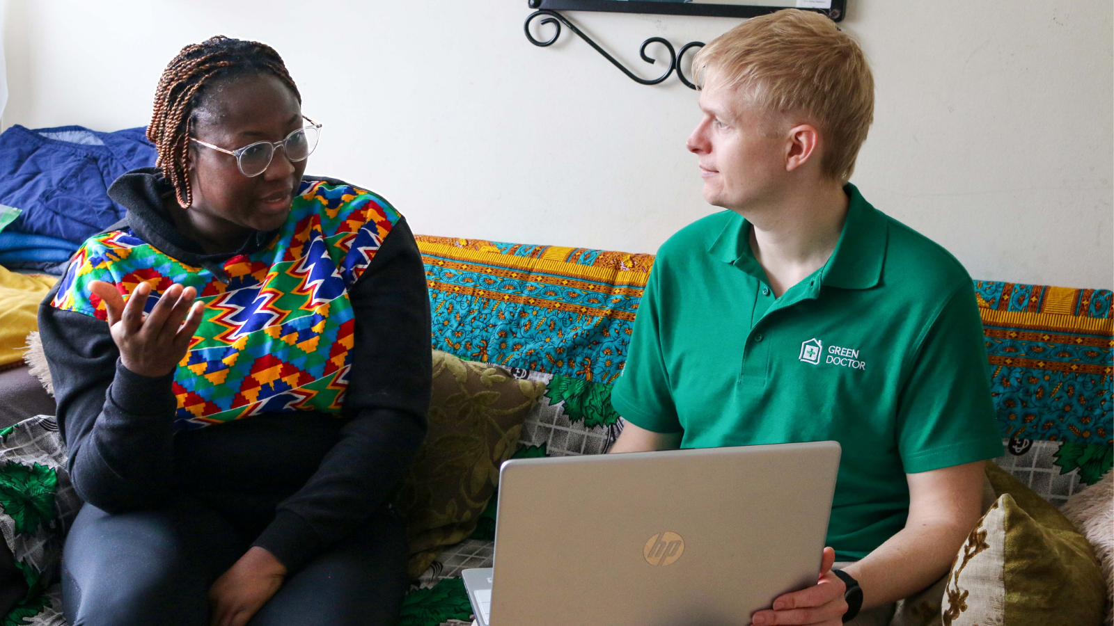 Green doctor with laptop speaking to service user on her sofa. This shows what green doctor home visits look like and how we can help you with the rising energy prices.