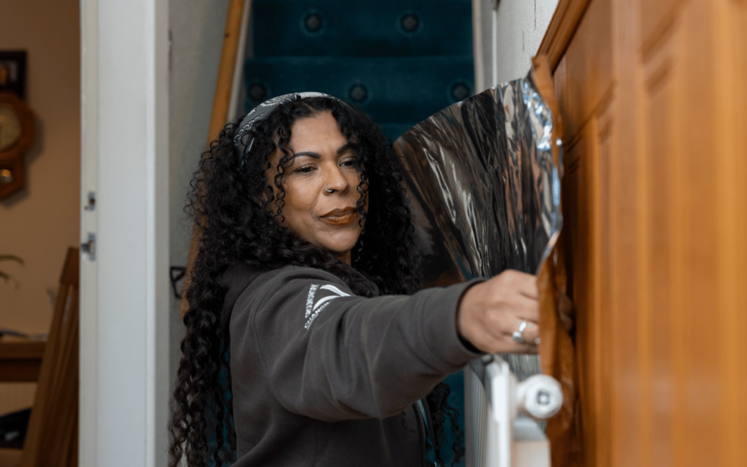 Green Doctor installing radiator foils behind a radiator showing one of the measures you can take to save energy.